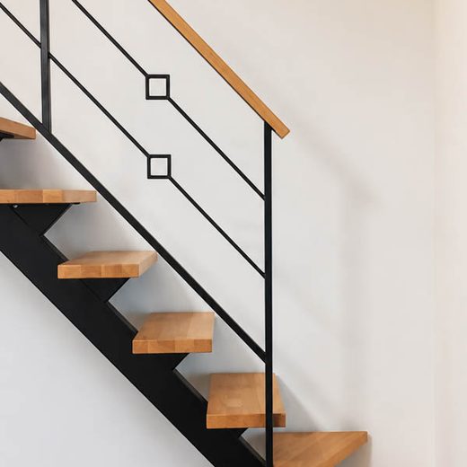 Unutrašnje jednoosovinske stepenice sa crnom konstrukcijom, drvenim gazištima i minimalističkom ogradom sa romb detaljima
