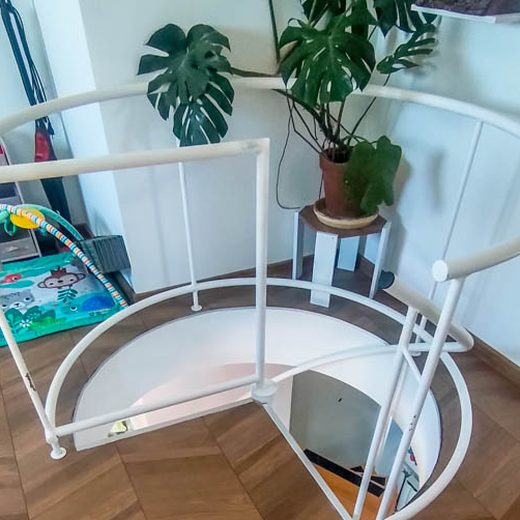 Pogled odozgo na belu zaštitnu kružnu ogradu i otvor u ploči za spiralno stepenište