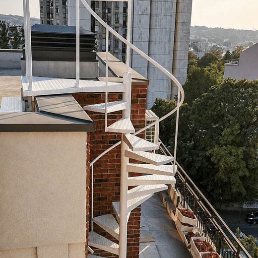 Bledo belo spoljno spiralno metalno stepenište od rebrastog lima za izlaz na krovnu terasu